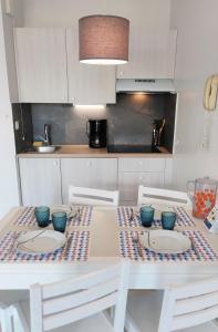 una cocina con una mesa blanca con tazones azules. en Appartement 2 pièces dans résidence bord de mer aux Sables d'Olonne en Les Sables-dʼOlonne