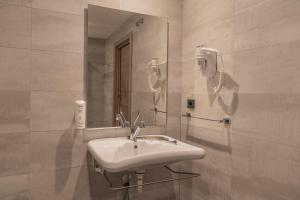 a white bathroom with a sink and a mirror at Hotel NERU con Encanto in León