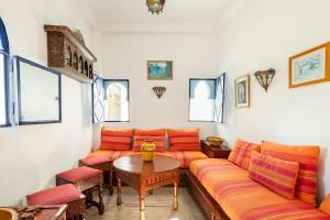 salon z pomarańczowymi kanapami i stołem w obiekcie DAR YAMNA Maison typique Kasbah de Tanger w mieście Tanger