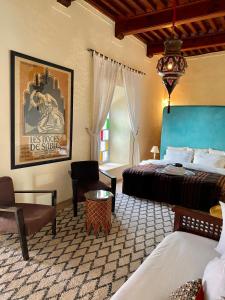 a bedroom with a bed and a chair and a table at Riad Tizwa Marrakech in Marrakesh