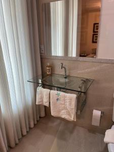 uma casa de banho com um lavatório de vidro e um espelho. em Vilage Bed & Breakfast em Volta Redonda