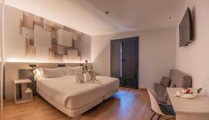 a bedroom with a large white bed and a table at Hotel NERU con Encanto in León