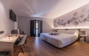 a bedroom with a large bed and a desk and a television at Hotel NERU con Encanto in León