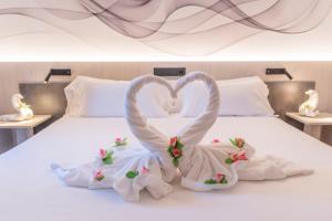 two swans made out of towels sitting on a bed at Hotel NERU con Encanto in León
