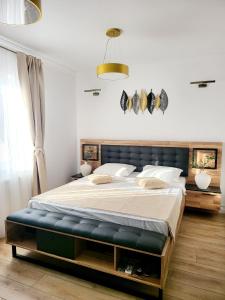 a bedroom with a large bed with a bench around it at House of Chess Luxury Villa in Satu Mare