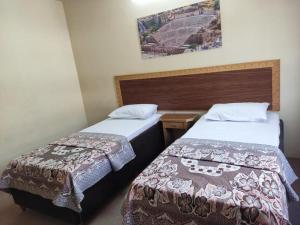 2 camas en una habitación de hotel con una foto en la pared en Asia Hotel, en Amán