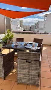 einen Tisch und Stühle auf einem Balkon mit Sonnenschirm in der Unterkunft Apartamento T2 com Terraço grande in Quarteira