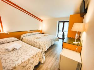 um quarto de hotel com duas camas e uma televisão em Albergo B&B Tenesi em Manerba del Garda
