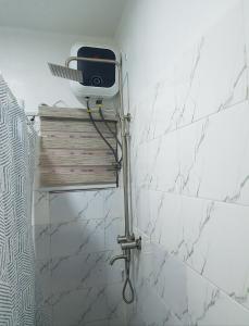 a white tiled bathroom with a shower curtain at Andrea’s Home in Abuja