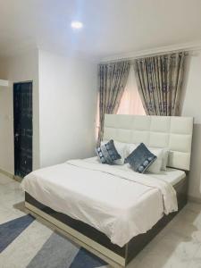 a bedroom with a large white bed with a window at Andrea’s Home in Abuja