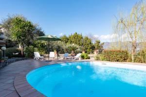 a swimming pool with chairs and an umbrella at Villa Renetta with Swimming pool and Jacuzzi and parking in Rapallo