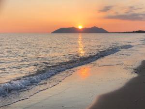 um pôr do sol na praia com uma montanha ao fundo em La Casina di Tonia em Terracina