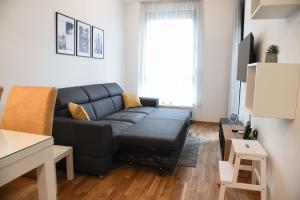 uma sala de estar com um sofá preto e uma janela em ANNA 2 Apartment free parking em Novi Sad