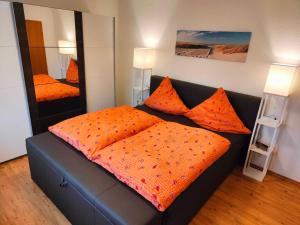 Un dormitorio con una cama con almohadas naranjas. en Ferienwohnung Leezdorf, en Leezdorf