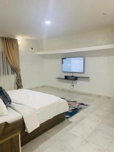 a bedroom with a bed and a flat screen tv at Andrea’s Home in Abuja