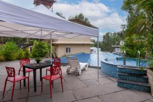 eine Terrasse mit Tisch und Stühlen und einem Pool in der Unterkunft StayVista's Chimney Cottage with Sprawling Lawns, Picturesque Views, Plunge Pool, Jacuzzi, and Home Theatre in Panchgani