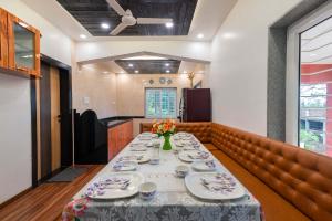 ein Esszimmer mit einem langen Tisch mit Tellern in der Unterkunft StayVista's Chimney Cottage with Sprawling Lawns, Picturesque Views, Plunge Pool, Jacuzzi, and Home Theatre in Panchgani