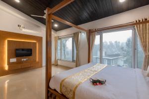 ein Schlafzimmer mit einem großen Bett und einem großen Fenster in der Unterkunft StayVista's Chimney Cottage with Sprawling Lawns, Picturesque Views, Plunge Pool, Jacuzzi, and Home Theatre in Panchgani + 27 Fotos