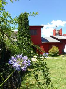 a garden with purple flowers and a red building at Casa Bordó, B & B in Tandil