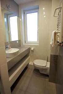 uma casa de banho com um lavatório, um WC e uma janela. em Pod Różami em Grzybowo
