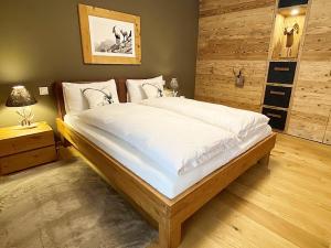 una camera da letto con un grande letto con lenzuola bianche di Alpenstil, 4 Pax, zentral, 1 Parkplatz - RE31 a Sankt Moritz