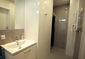 a white bathroom with a sink and a shower at Pod Różami in Grzybowo