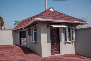 ein kleines weißes Haus mit rotem Dach in der Unterkunft TFP Lodge in Ibadan