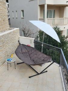 a hammock with an umbrella on a balcony at Apartments - Villa Sabrina in Brela