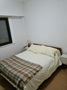 1 dormitorio con 1 cama con manta y ventana en Departamento Playa Bristol Casino en Mar del Plata