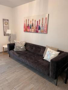 a brown couch in a living room with a painting of wine bottles at Ostfrieslands Perle Ferienwohnung an der Nordseeküste, Sauna, Terrasse, Garten, ruhige Lage, WLAN in Norden
