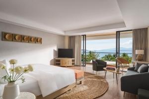 a bedroom with a large white bed and a living room at Boma Resort Nha Trang in Nha Trang
