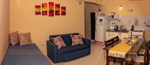 sala de estar con sofá azul y cocina en Dto Ha Naca Ushuaia en Ushuaia