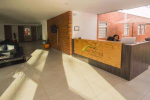 a woman sitting at a counter in an office with a laptop at Hotel Valle de San Nicolas in Rionegro