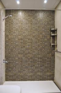 a bathroom with a shower with a tiled wall at Axxodia Cairo Festival Residence in Cairo