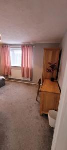 Habitación con escritorio y ventana con cortinas rosas. en Rent Unique the Beeches 2bed, en Crawley