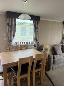 a dining room table with chairs and a couch at 3 Bed Platinum Caravan PRESTHAVEN SANDS in Prestatyn