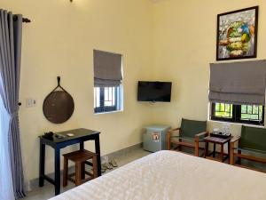 a bedroom with a bed and chairs and a tv at Yen villa Hội An in Hoi An