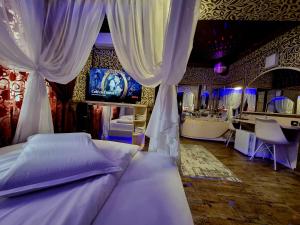 een slaapkamer met een bed met gordijnen en een televisie bij Hotel Boutique Mikaela (Adult Only) in Braşov