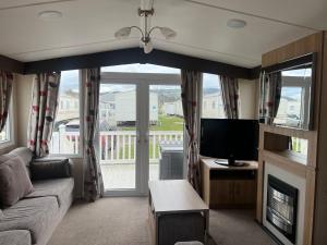 a living room with a couch and a television at 3 Bed Platinum Caravan PRESTHAVEN SANDS in Prestatyn