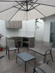 patio z 2 krzesłami, stołem i parasolem w obiekcie Tumbes Zorritos Bocapan Casa con piscina 3 dormitorios w mieście Bocapán
