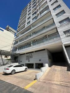 une voiture blanche garée devant un grand bâtiment dans l'établissement Departamento en Corrientes, à Corrientes