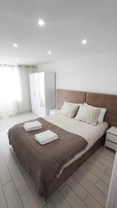 a bedroom with a large bed with two towels on it at Lemon Tree House Coimbra - Courtyard garden with city views in Coimbra
