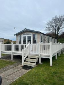 a white mobile home with a porch and stairs at 3 Bed Platinum Caravan PRESTHAVEN SANDS in Prestatyn