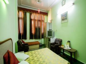 a hotel room with a bed and chairs and a television at Hotel Woodland Deluxe in New Delhi