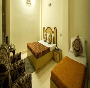 a hotel room with two beds and a chair at Hotel Woodland Deluxe in New Delhi