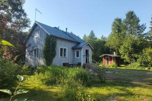 una pequeña casa blanca en medio de un patio en Villa Mäntysaari luonnonrauhaa kaupungin lähellä., en Kontiolahti