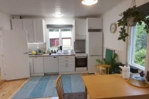 a kitchen with white cabinets and a table and a dining room at Villa Mäntysaari luonnonrauhaa kaupungin lähellä. in Kontiolahti