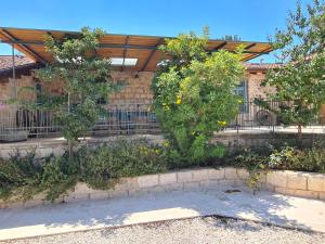 un edificio con una valla y algunos árboles y flores en צימר חצר שמואלי - יחידת אירוח זוגית במושב אילניה en Ilaniyya