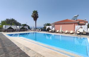 a large swimming pool with chairs and umbrellas at Saint George's Hotel in Nea Stira
