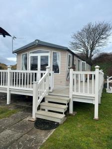 a large white house with a porch and stairs at 3 Bed Platinum Caravan PRESTHAVEN SANDS in Prestatyn